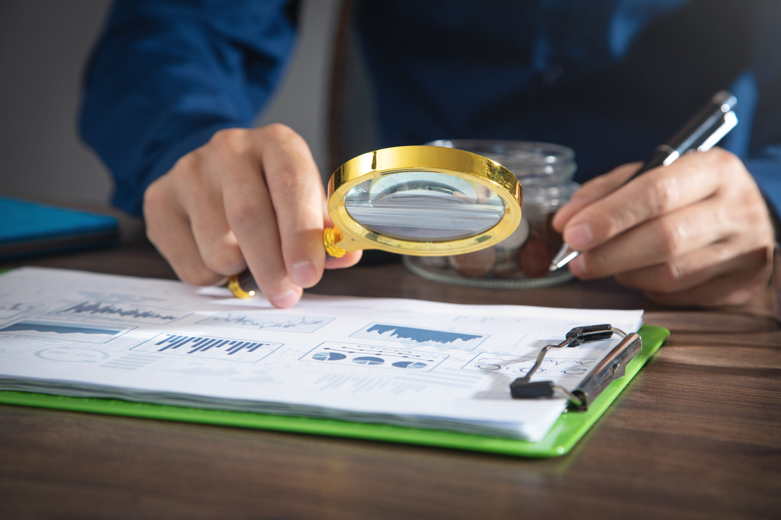 Man holding magnifying glass with a graphs and charts. Business.